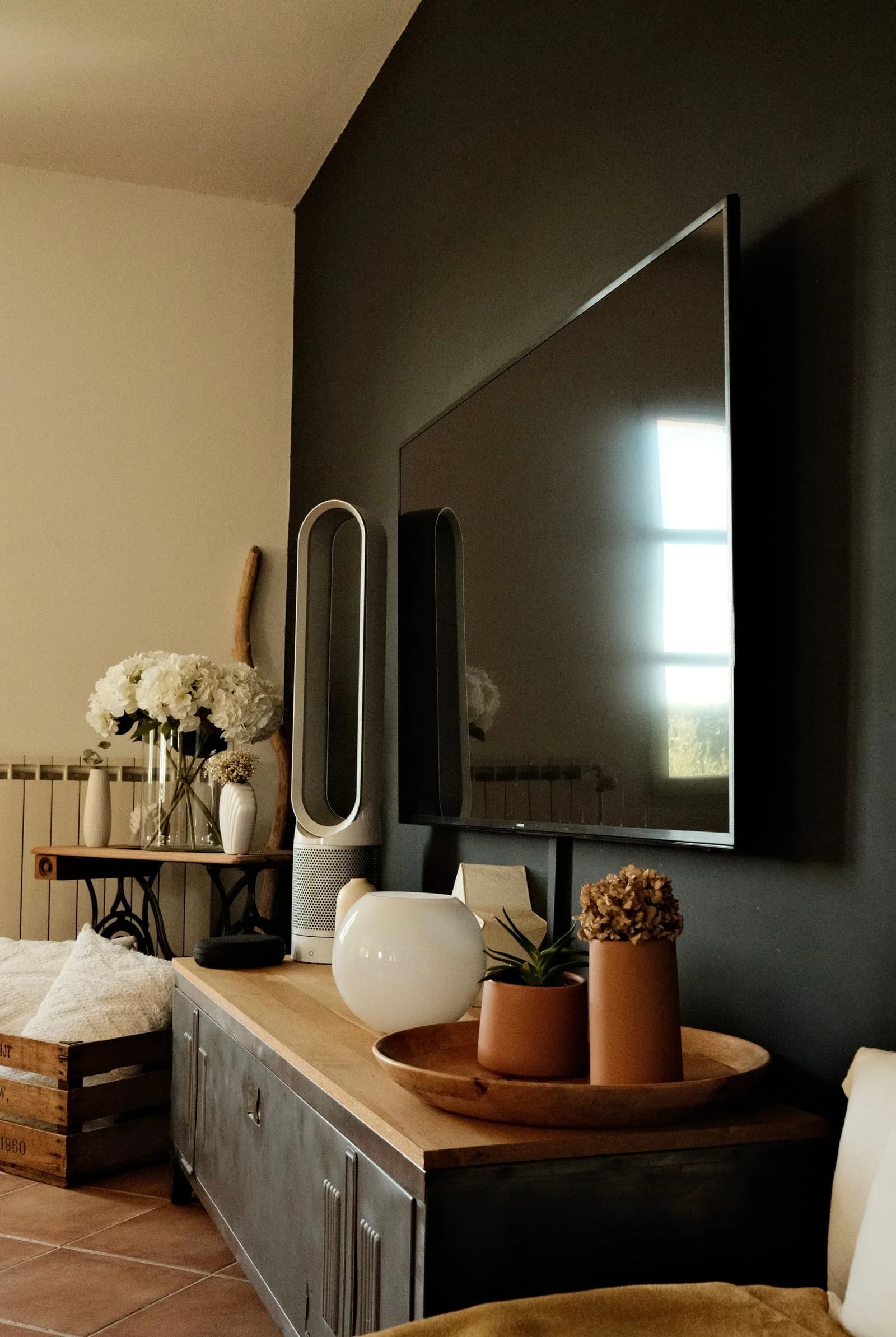 Mueble bajo de frentes oscuros y tapa de madera, ubicado debajo de un televisor.